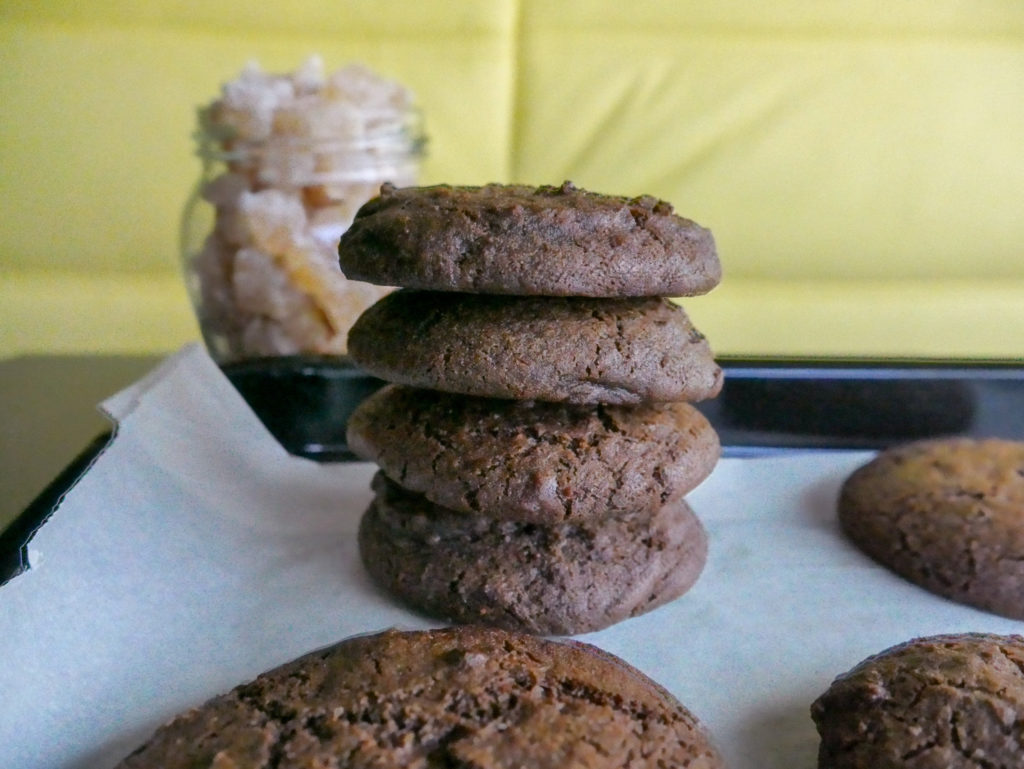 a tower of ginger molasses cookies with candied ginger behind it