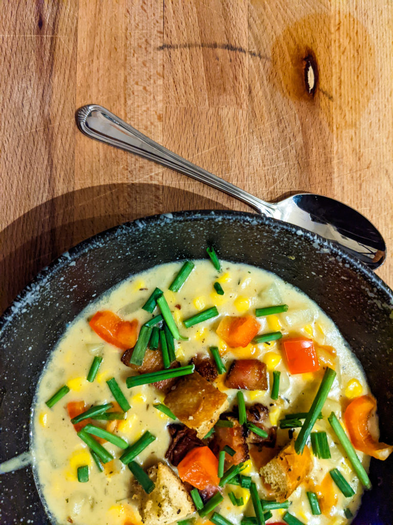 corn chowder with croutons on top and silver spoon