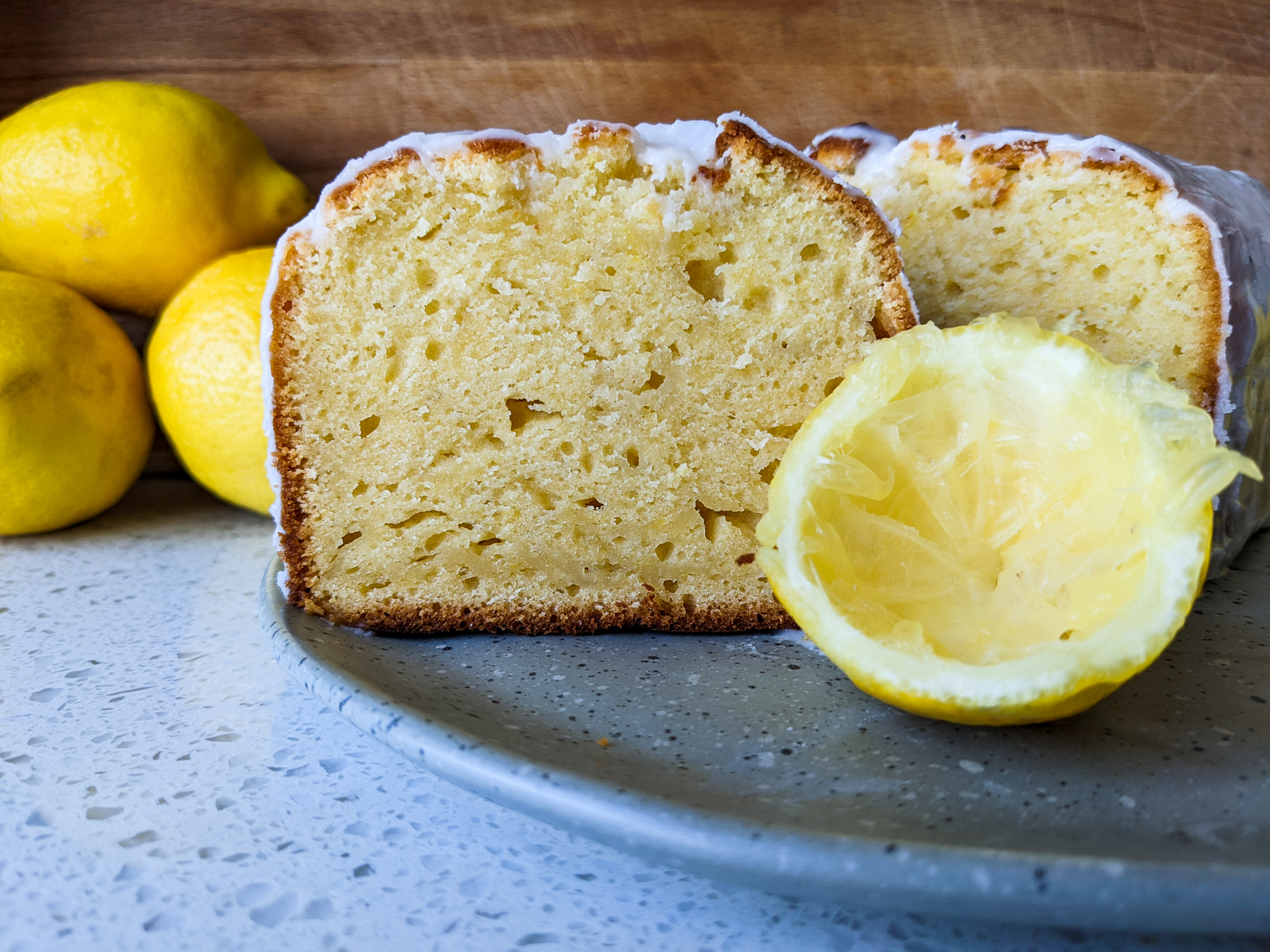 Lemon loaf cake cut in half with a juiced half lemon